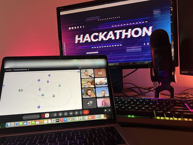 A laptop with the hackathon call next to a monitor showing the word Hackathon